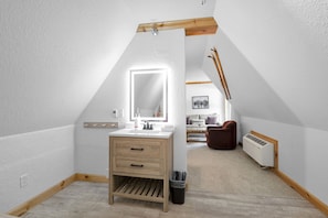 A modern bathroom with a wooden vanity, a large mirror, and a radiator. - Selkirk Split King - Family Suite with Balcony (Sandpoint)