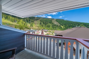 A balcony with a white railing, overlooking a mountainous landscape with a clear sky.
