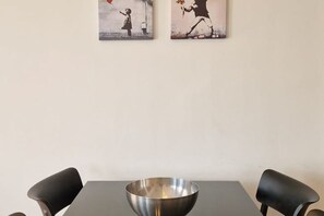 A dining area with a table, two chairs, and a metal bowl. - Style Homes (Milan)
