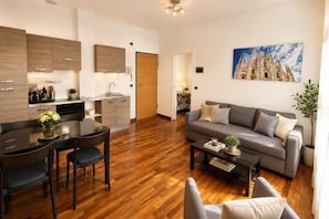 A modern living room with a sofa, coffee table, and dining area. - Style Homes (Milan)