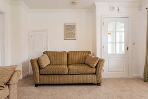 A living room with a striped sofa, a door, and a framed artwork on the wall. - Toast Stays - The Peth House (Shildon)