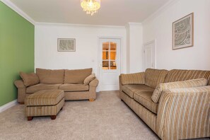 A living room with two sofas, a matching ottoman, and a chandelier. - Toast Stays - The Peth House (Shildon)