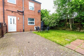 A brick house with a paved patio, a white door, and a satellite dish. - Toast Stays - The Peth House (Shildon)