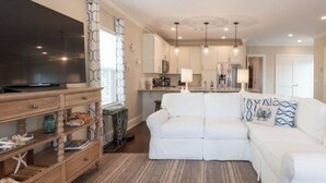 A modern living room with a white sofa, wooden entertainment unit, and a large flat-screen TV.