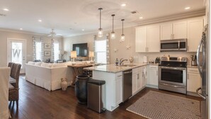 A modern kitchen with white cabinets, stainless steel appliances, and a dining area with a sofa and chairs.