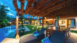Un espacio exterior moderno con piscina, sillas de descanso y una mesa de comedor.