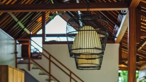 Una mesa de madera para comer con sillas, una lámpara colgante y un televisor al fondo.
