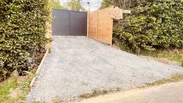 A gravel driveway leading to a wooden gate with a black fence.