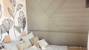 A bedroom with a bed, pillows, a wall with a geometric pattern, and a wall with a floral design. - Le Temps d'une Nuit (Landouzy-la-Ville)
