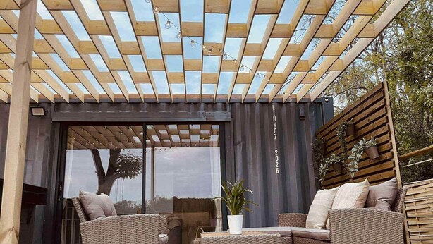 An outdoor patio with wicker furniture, a pergola, and a view through large glass doors. - Le Temps d'une Nuit (Landouzy-la-Ville)