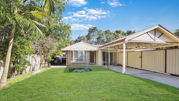A residential property with a well-maintained lawn, a covered patio, and a garage.