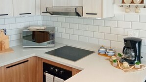 Une cuisine moderne avec des meubles en bois clair, une cuisinière en acier inoxydable, un four encastré, un four à micro-ondes et une machine à café.