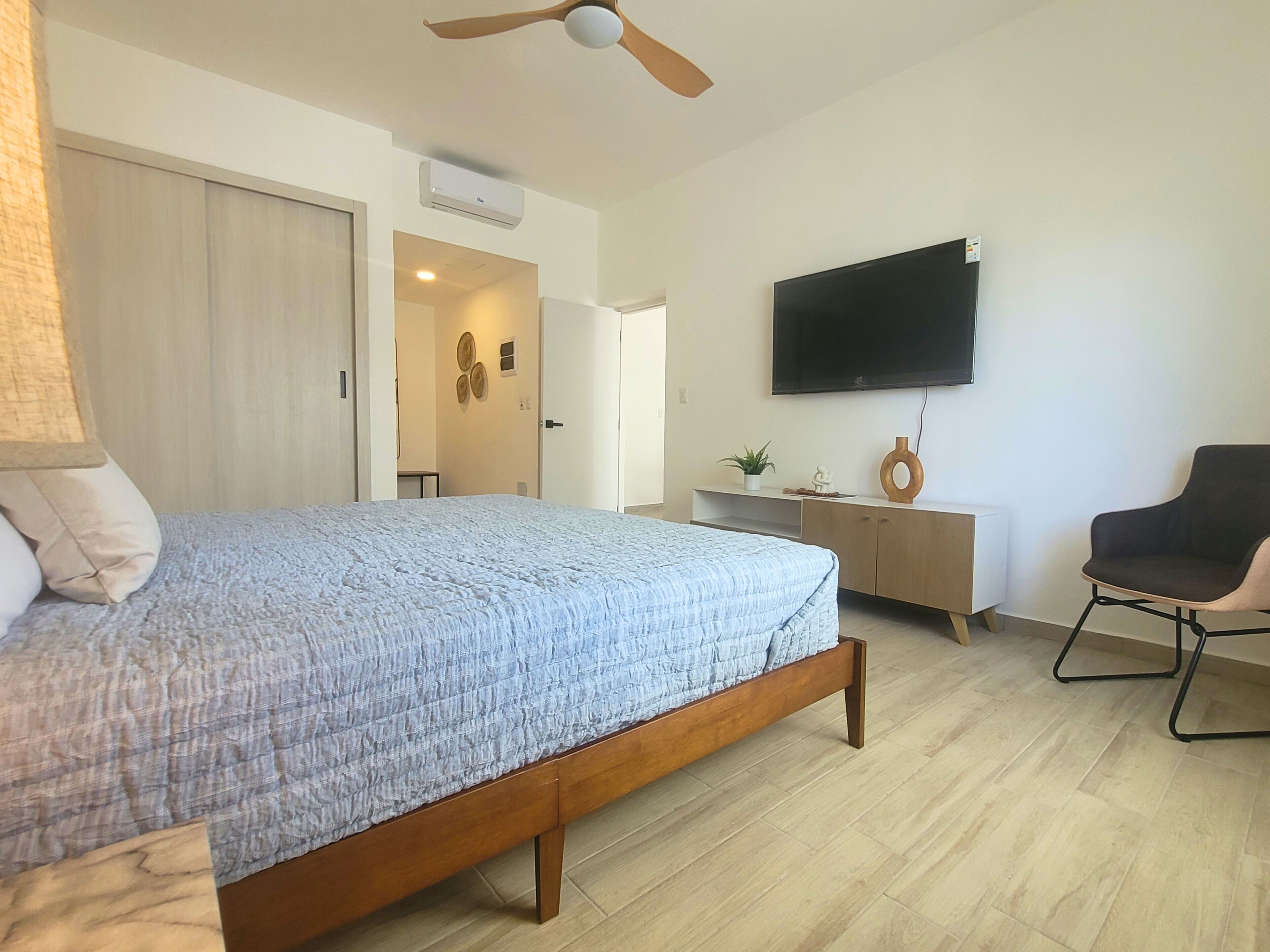 A bedroom with a bed, a TV, a desk, and a chair.