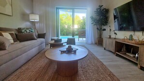 Un salon moderne avec un canapé, une table basse et un grand téléviseur fixé au mur.