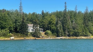 A house by a lake surrounded by dense forest.