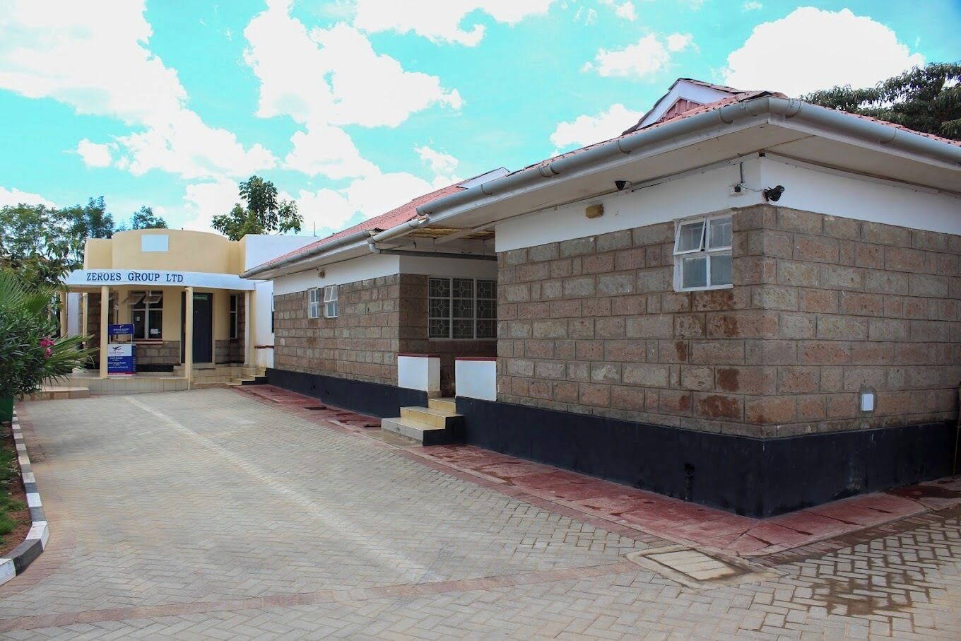 A building with a brick facade, a flat roof, and a paved entrance area.