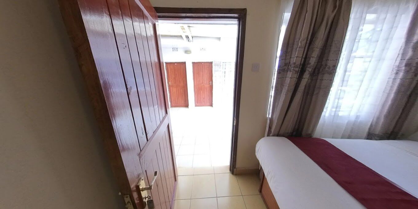 Ein Zimmer mit einem Bett, einer Holztür und Blick durch eine offene Tür.