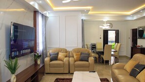 Una sala moderna con sofás de cuero, un televisor de pantalla plana y un comedor con mesa y sillas.