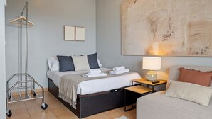 Quarto de hotel moderno com cama, mesa de cabeceira, abajur e um quadro abstrato grande na parede.