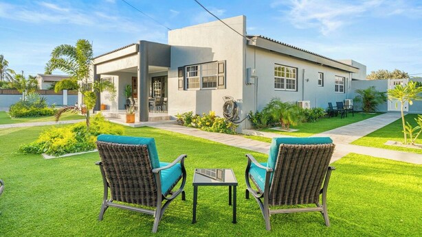 Een modern huis met een patio, compleet met twee rieten stoelen en een kleine tafel.