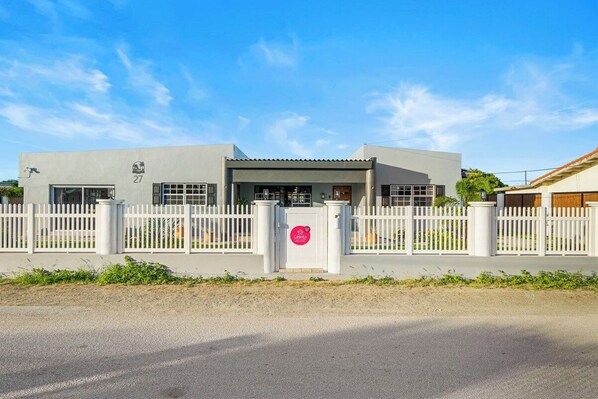A building with a gated entrance, a sign indicating a specific area, and a clear sky. - Incredible 4 BR Home with Private Pool Near Ocean (Pos Chiquito)