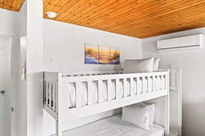 Habitación con literas, techo de madera, un cuadro en la pared y un equipo de aire acondicionado.
