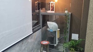 Ein kleines, modernes Badezimmer mit Duschkabine aus Glas, einem Hocker und einem Blumentopf.