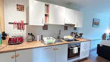 Eine moderne Küche mit weißen Schränken, einer Holz Arbeitsplatte, einem Toaster, einer Spüle und einem Herd.