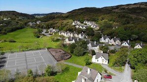 A residential area with houses, a parking lot, and a green field.