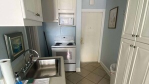 A compact kitchen with white cabinets, a stainless steel sink, a microwave, and a stove. - Charming Studio condo in excellent Daytona Beach (Daytona Beach)