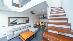 Een modern interieur met een trap, een eethoek en een zithoek.