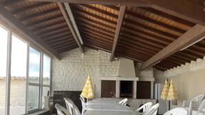 A spacious outdoor dining area with white plastic chairs and a large table, stone walls, and a wooden ceiling. - Guest Room 'Room 1 for 2 People' with Shared Pool, Shared Terrace and Wi-Fi (Segonzac)