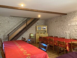 A dining area with a long table covered in red, surrounded by wooden chairs. A staircase leads to an upper level. - Guest Room 'Room 1 for 2 People' with Shared Pool, Shared Terrace and Wi-Fi (Segonzac)
