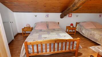 A room with two wooden beds, a wooden ceiling, and a radiator.