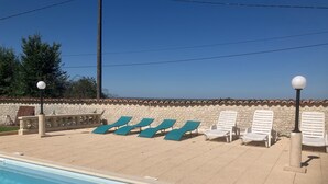 A swimming pool with lounge chairs and a stone wall. - Guest Room 'Lavande 4 Persons' with Shared Pool, Shared Terrace and Wi-Fi (Segonzac)