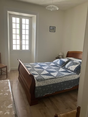 A bedroom with a wooden bed, a window, a chair, and a nightstand with a lamp. - Bed and Breakfast 'D'hôtes' with Shared Pool, Shared Terrace and Wi-Fi (Segonzac)