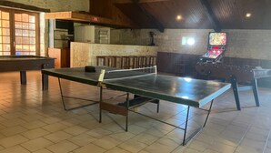 A ping pong table in a room with a stone wall, wooden ceiling, and a foosball table. - Bed and Breakfast 'D'hôtes' with Shared Pool, Shared Terrace and Wi-Fi (Segonzac)