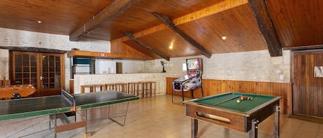 Una sala de billar con mesa de billar, mesa de futbolín y zona de bar.