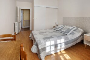 A bedroom with a bed, a chair, a bedside table, a radiator, and a door leading to another room. - Guest Room 'Room #4 - 2 Persons' with Shared Pool, Shared Terrace and Wi-Fi (Segonzac)