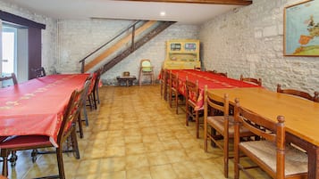Un espace repas avec une longue table et des chaises en bois, un escalier et une carte accrochée au mur.
