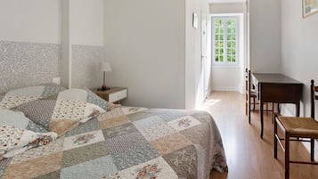 A bedroom with a bed, a nightstand, a desk, and a chair.