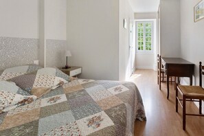 Une chambre à coucher avec un lit, une table de chevet, un bureau et une chaise.