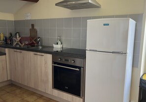 A kitchen with a stainless steel oven, a white refrigerator, and grey tiled backsplash. - Bed and Breakfast 'Chambre 4 - 2 Personnes' with Shared Pool, Shared Terrace and Wi-Fi (Segonzac)