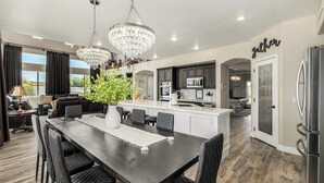 Une cuisine moderne avec des meubles de couleur sombre, un îlot central et des luminaires suspendus.