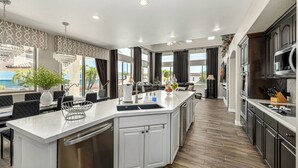 Une cuisine moderne dotée d’un îlot central, de meubles blancs et offrant une vue sur l’extérieur.