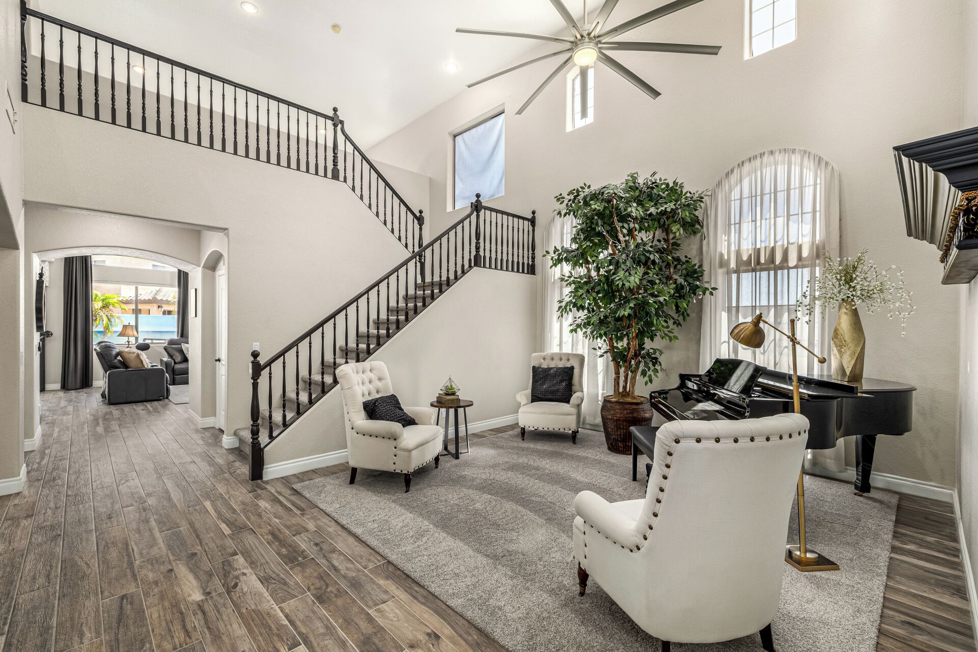 A spacious living area with a grand staircase, a piano, and comfortable seating.