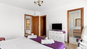 Une chambre d’hôtel équipée d’un lit, d’une télévision, d’un miroir dans la salle de bain et d’une porte donnant sur une autre pièce.