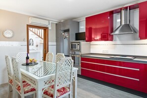 A kitchen with red cabinets, a microwave, and a dining table with chairs. - 'Villa Isabella' with Mountain Views, Wi-Fi and Air Conditioning (Alhaurín de la Torre)