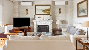 Un salon avec une cheminée, un téléviseur et un canapé.
