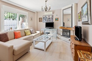 A living room with a sofa, coffee table, TV, fireplace, and large windows. - 'Villa Isabella' with Mountain Views, Wi-Fi and Air Conditioning (Alhaurín de la Torre)
